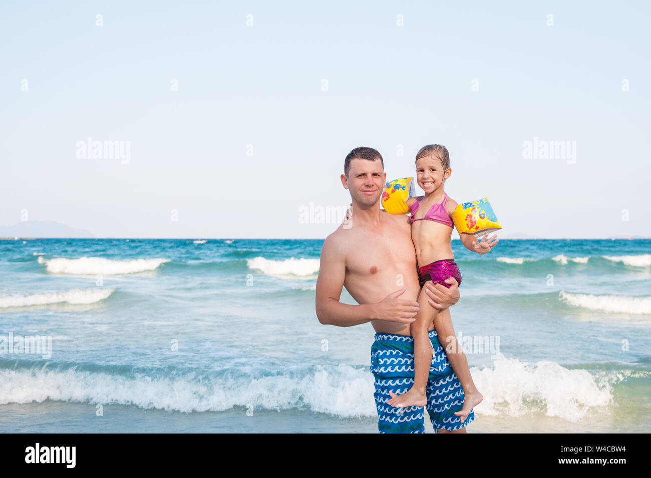 Father holding a baby high with happy face near the sea Stock Photo