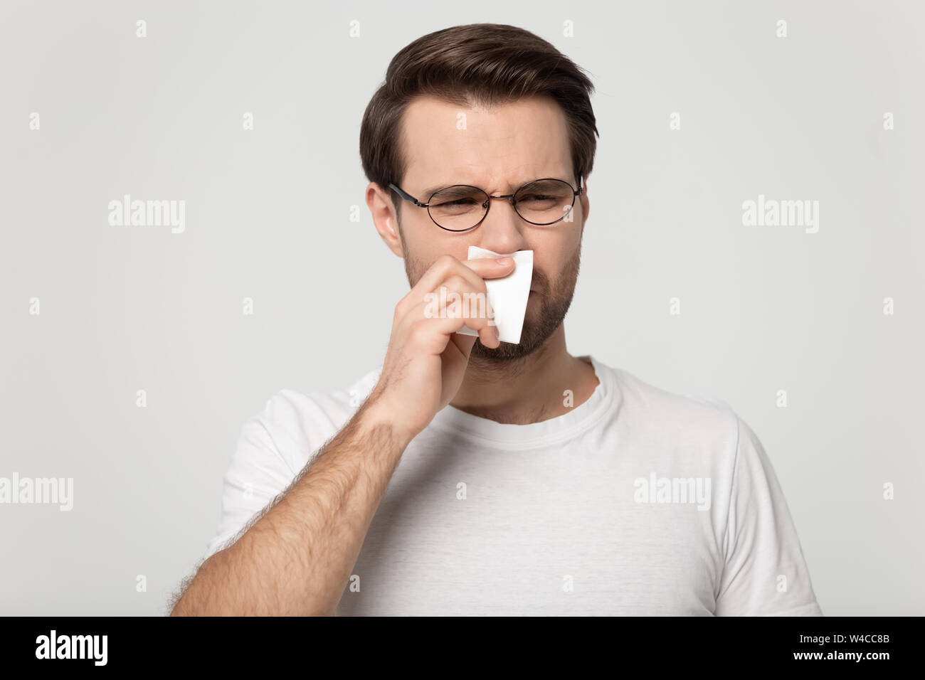 Sick guy sneezing wiping nose or suffers from unpleasant smell Stock Photo