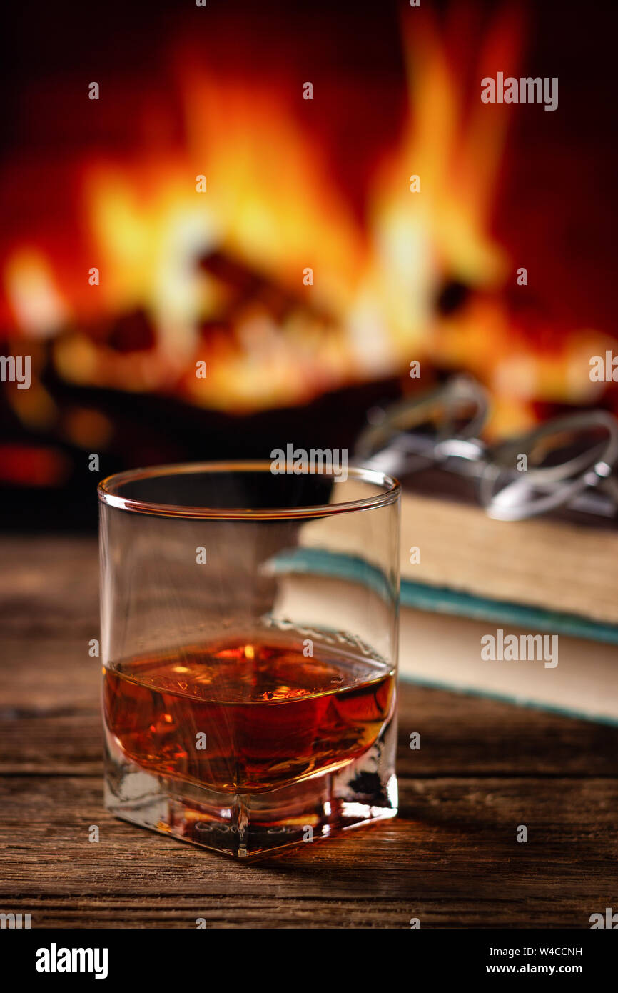 Glass of cognac or whiskey. Blur burning fireplace background Stock Photo Alamy