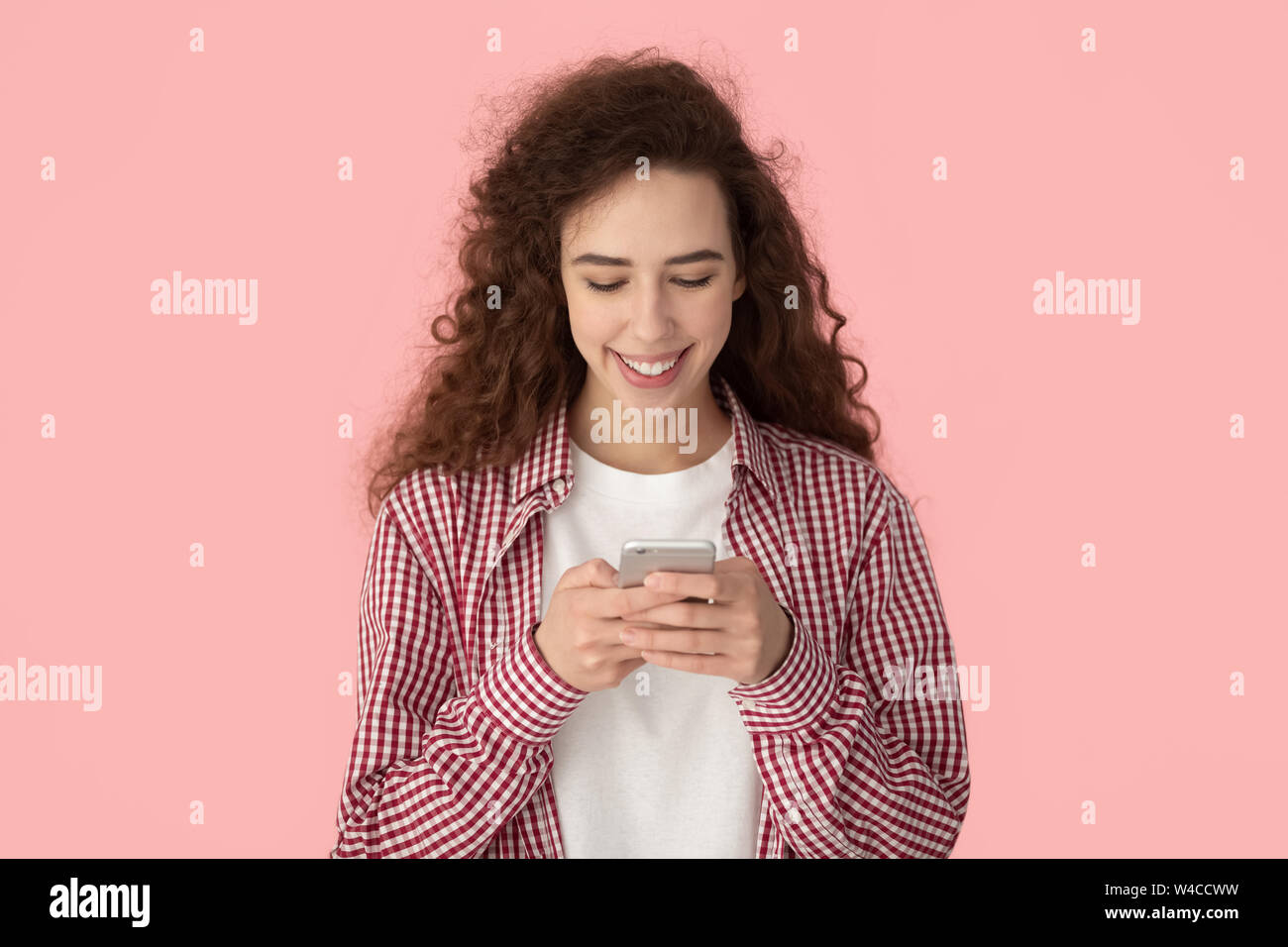 Young woman chatting using smartphone posing isolated on pink background Stock Photo