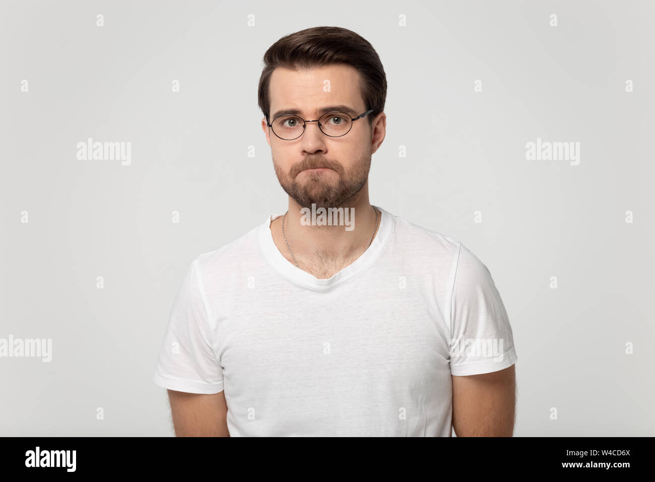 Upset guy with pursed lips posing isolated on gray background Stock Photo