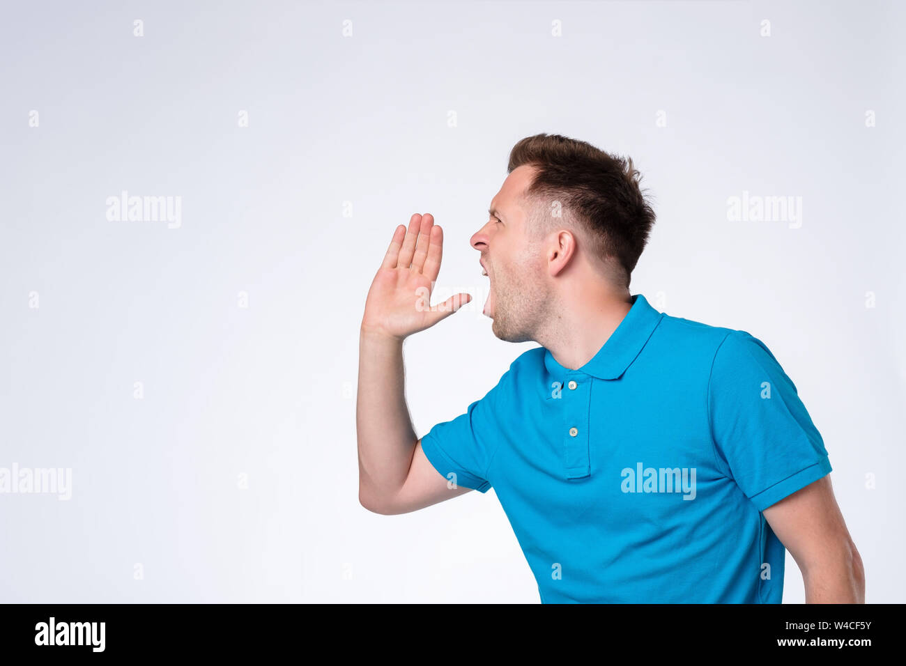 Handsome young man calling someone. Side view. Stock Photo
