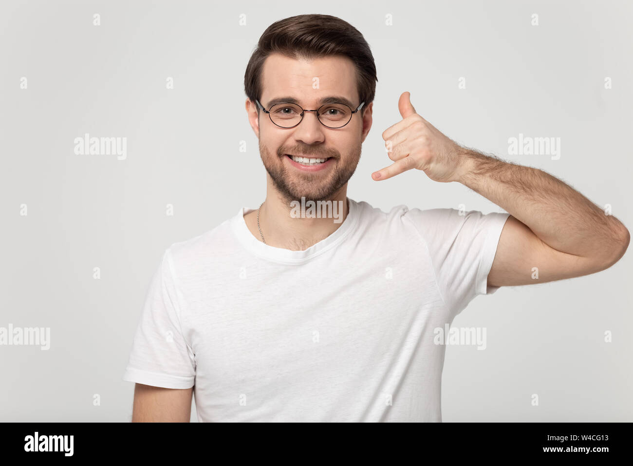 Guy showing call me back gesture with hand studio shot Stock Photo