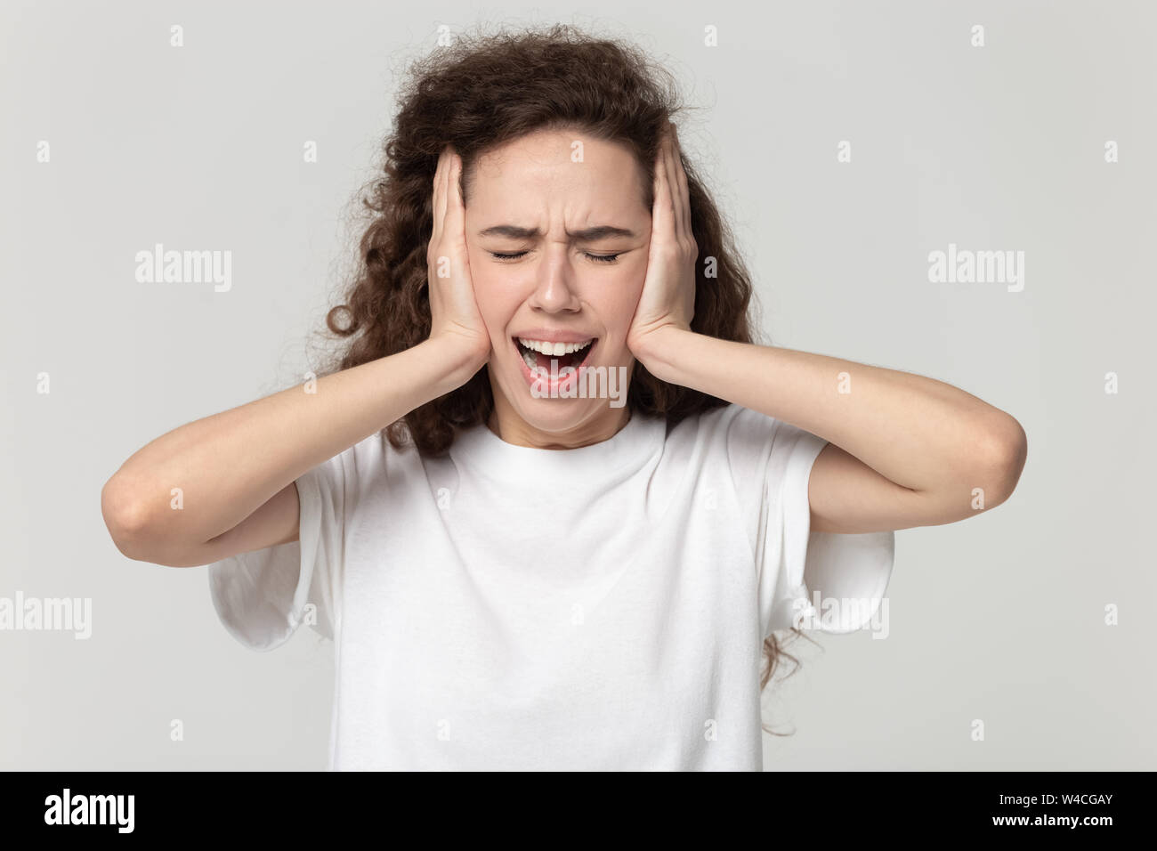 Woman cover ears with hands screaming feels furious studio shot Stock Photo