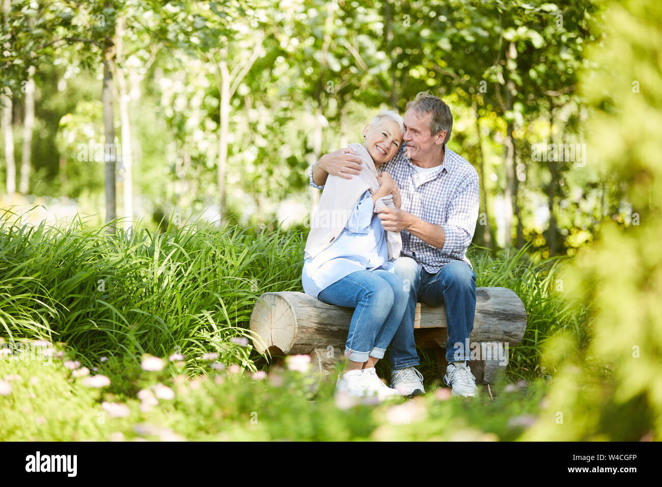 Full length portrait of loving senior couple embracing playfully while enjoying date in Summer park, copy space Stock Photo