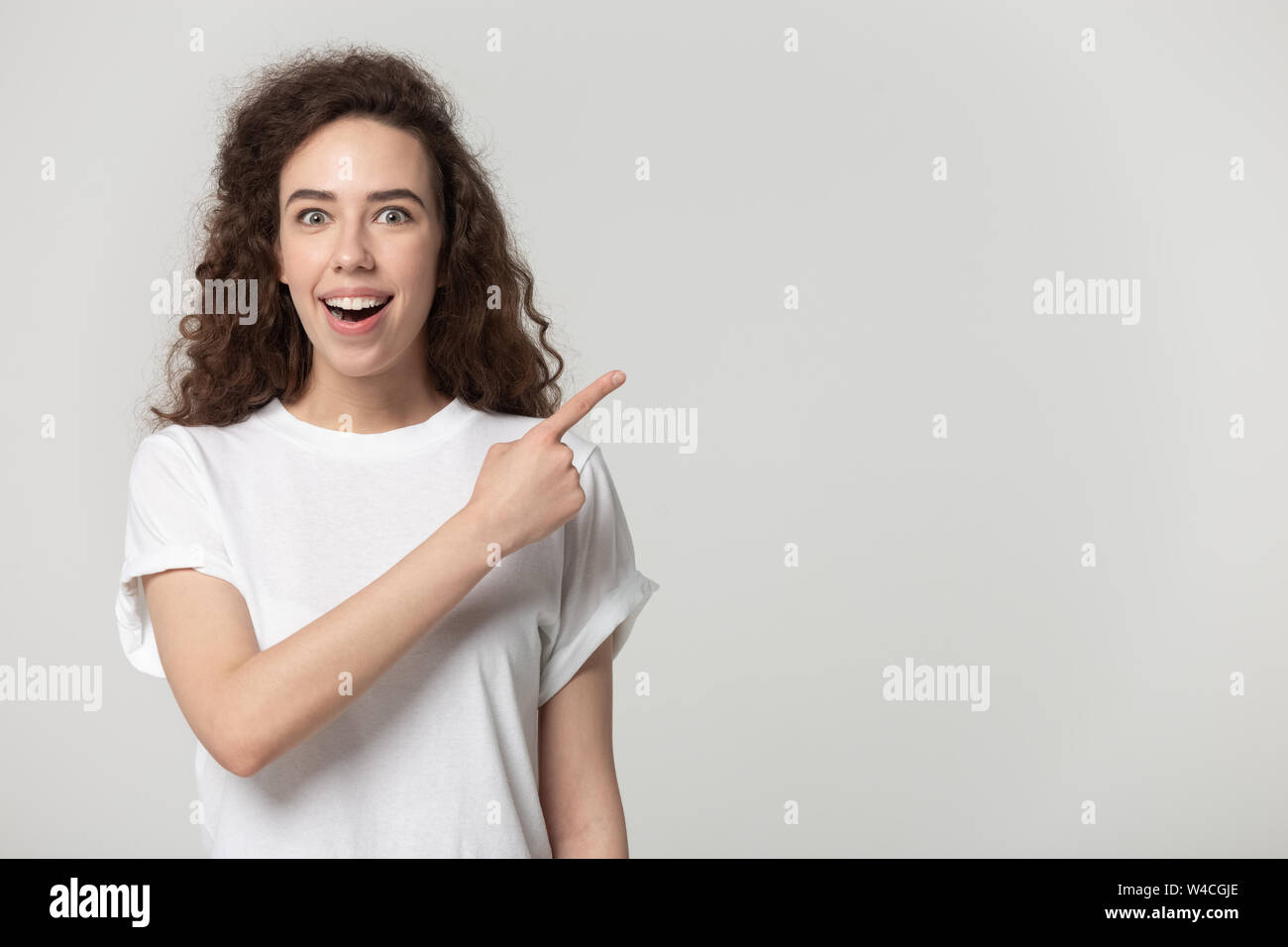 Surprised woman pointing finger at copy space studio shot Stock Photo