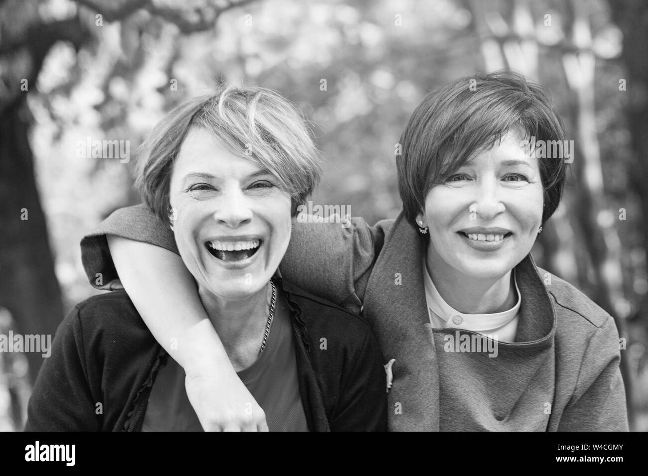 Laughing women hugging and having fun in park, tonned black and white retro portrait Stock Photo
