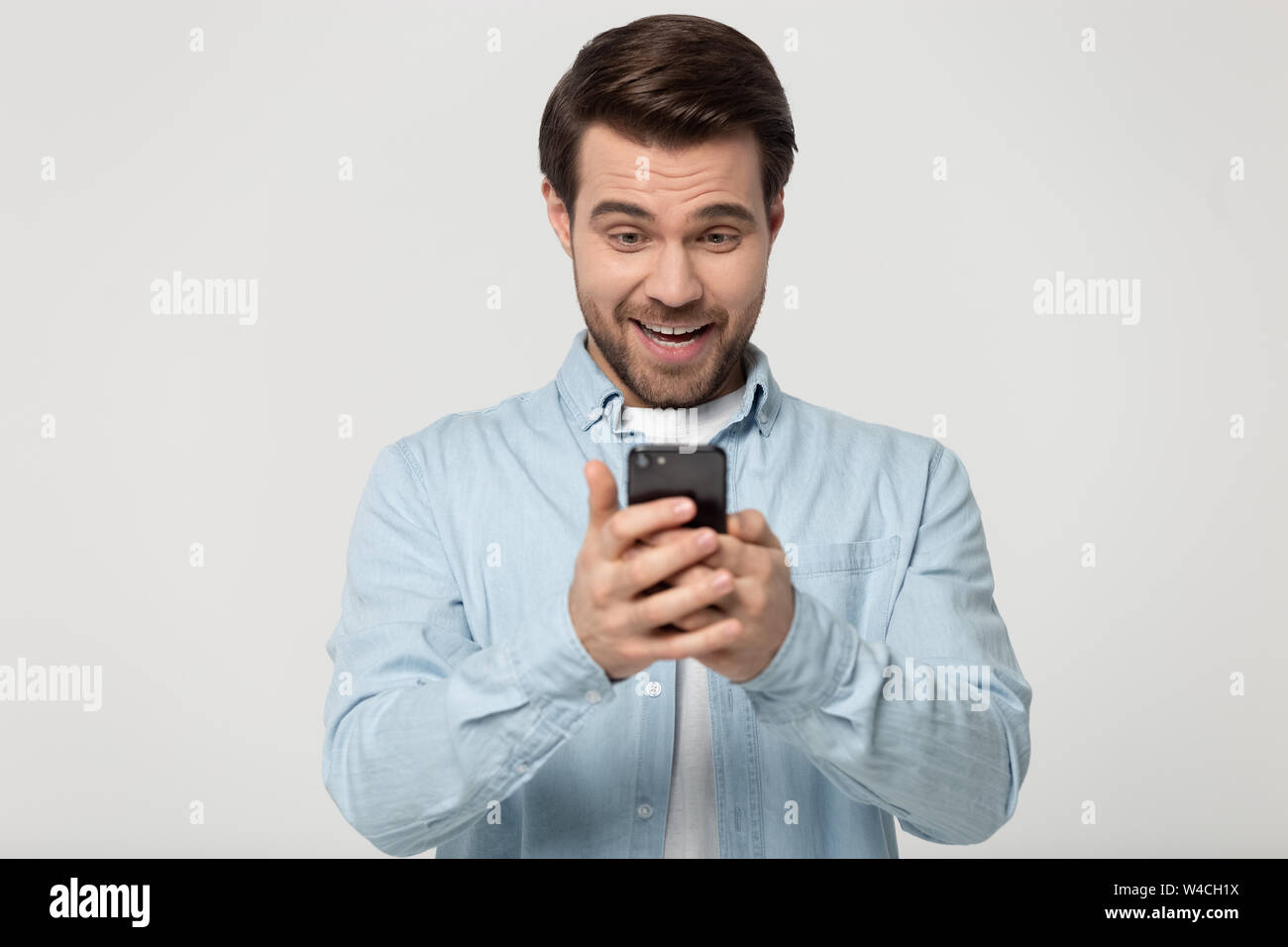 Man holding looking at smartphone feels surprised studio shot Stock Photo