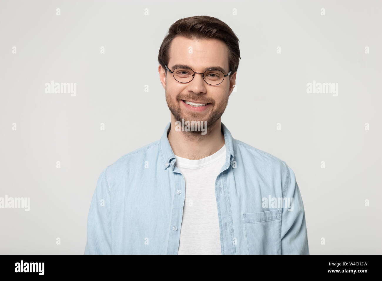 Attractive smiling young man in glasses studio headshot Stock Photo