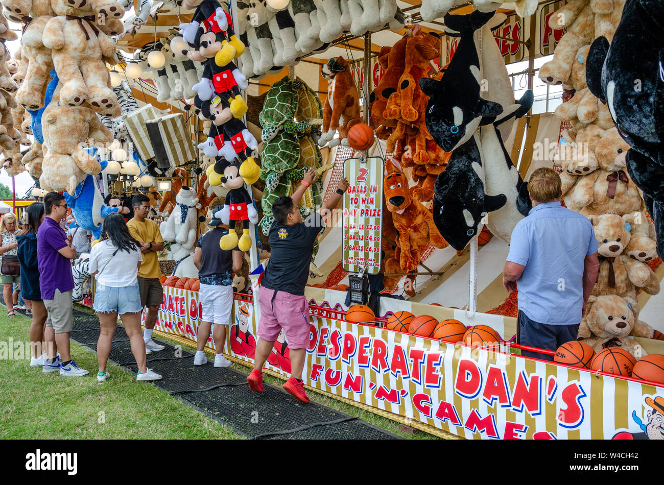 A fairground stall with lots of cuddly toys as prizes to entice players. You win by scoring baskets with a basket ball. Stock Photo