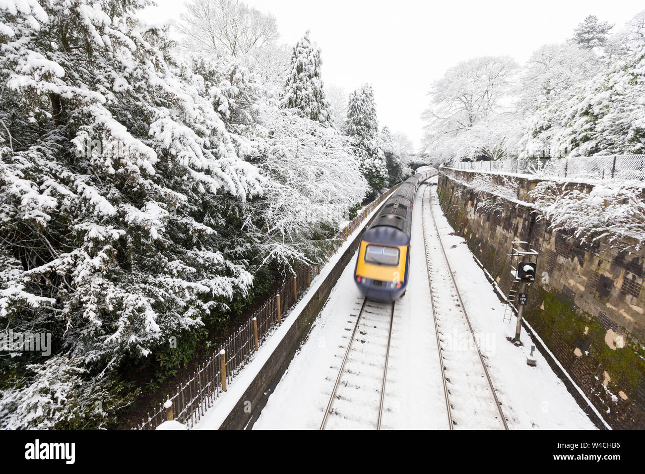 A British Intercity train travelling at speed on a snow-covered tracks through Sydney Gardens, a park in Bath, United Kingdom Stock Photo