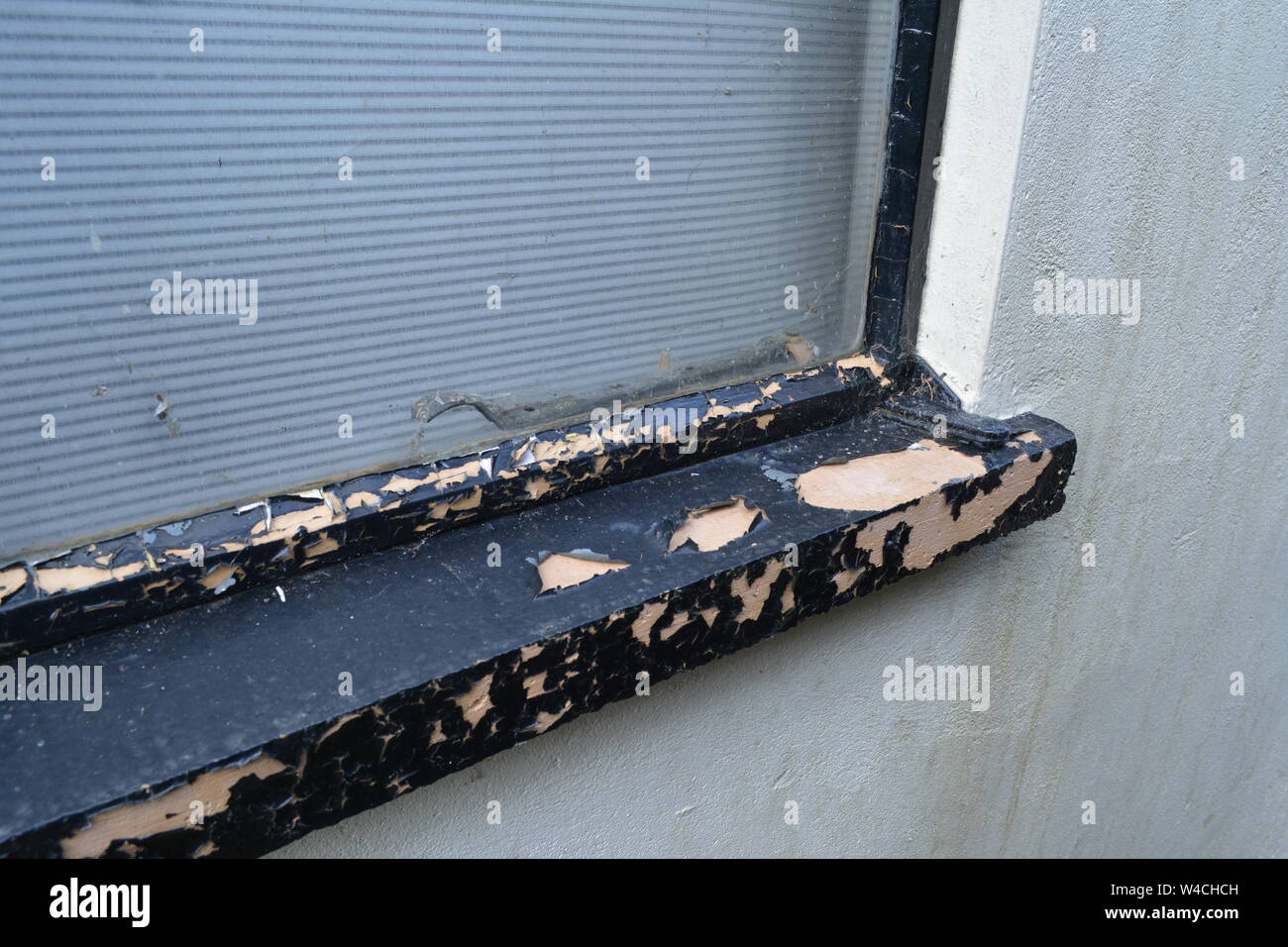 Black gloss paint peeling on metal framed house garage window and sill cill re house maintenance painting windows Stock Photo