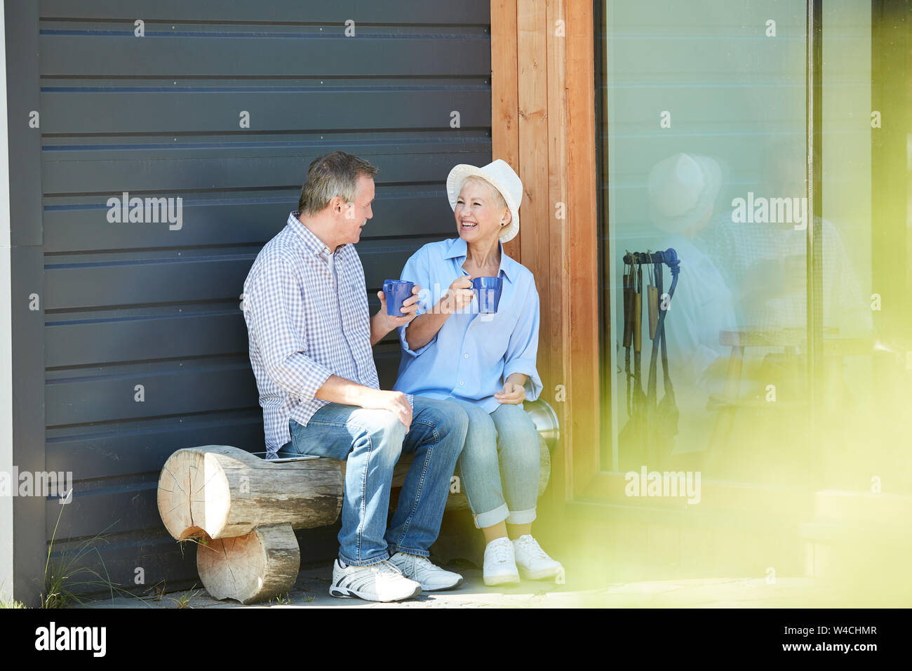 Full length portrait of contemporary mature couple laughing happily while drinking tea in back yard outdoors, copy space Stock Photo