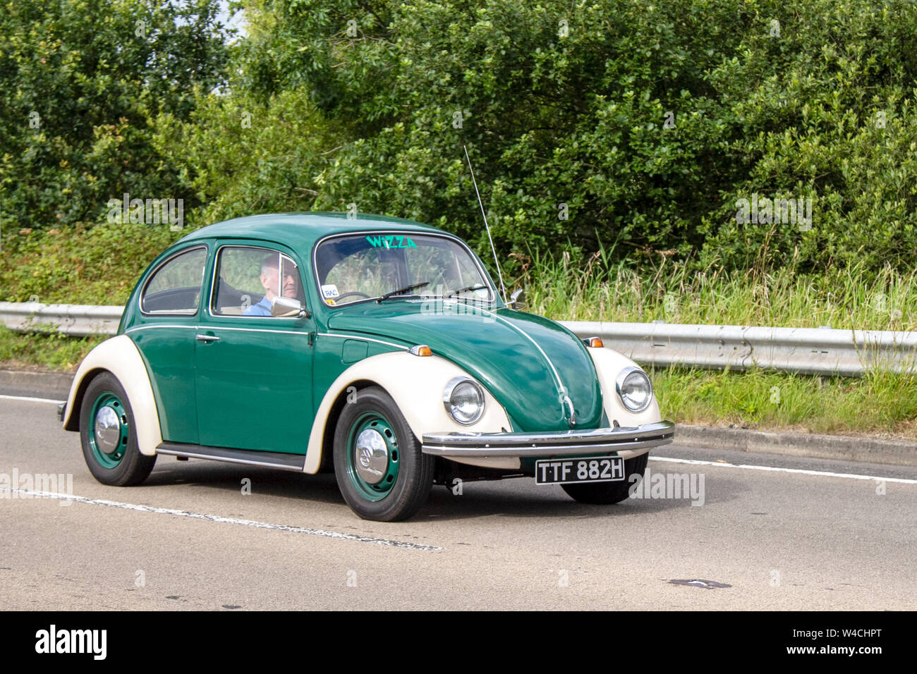 1969 60s green white old type VW Volkswagen 1500,  Käfer, Vocho, Fusca, Cocinelle, Maggiolino, Punch Buggy, People’s Car, air-cooled, rear-engined, rear-wheel-drive compact car. Vehicular traffic, moving vehicles, cars, vehicle driving on UK roads. Stock Photo
