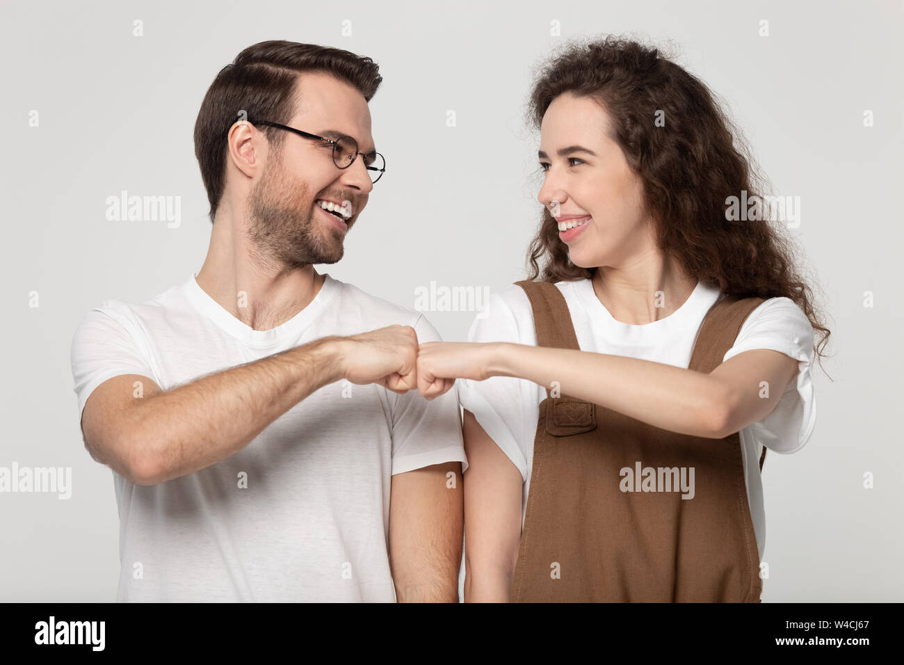 Girl guy smiling gives fist bump pose isolated on grey Stock Photo