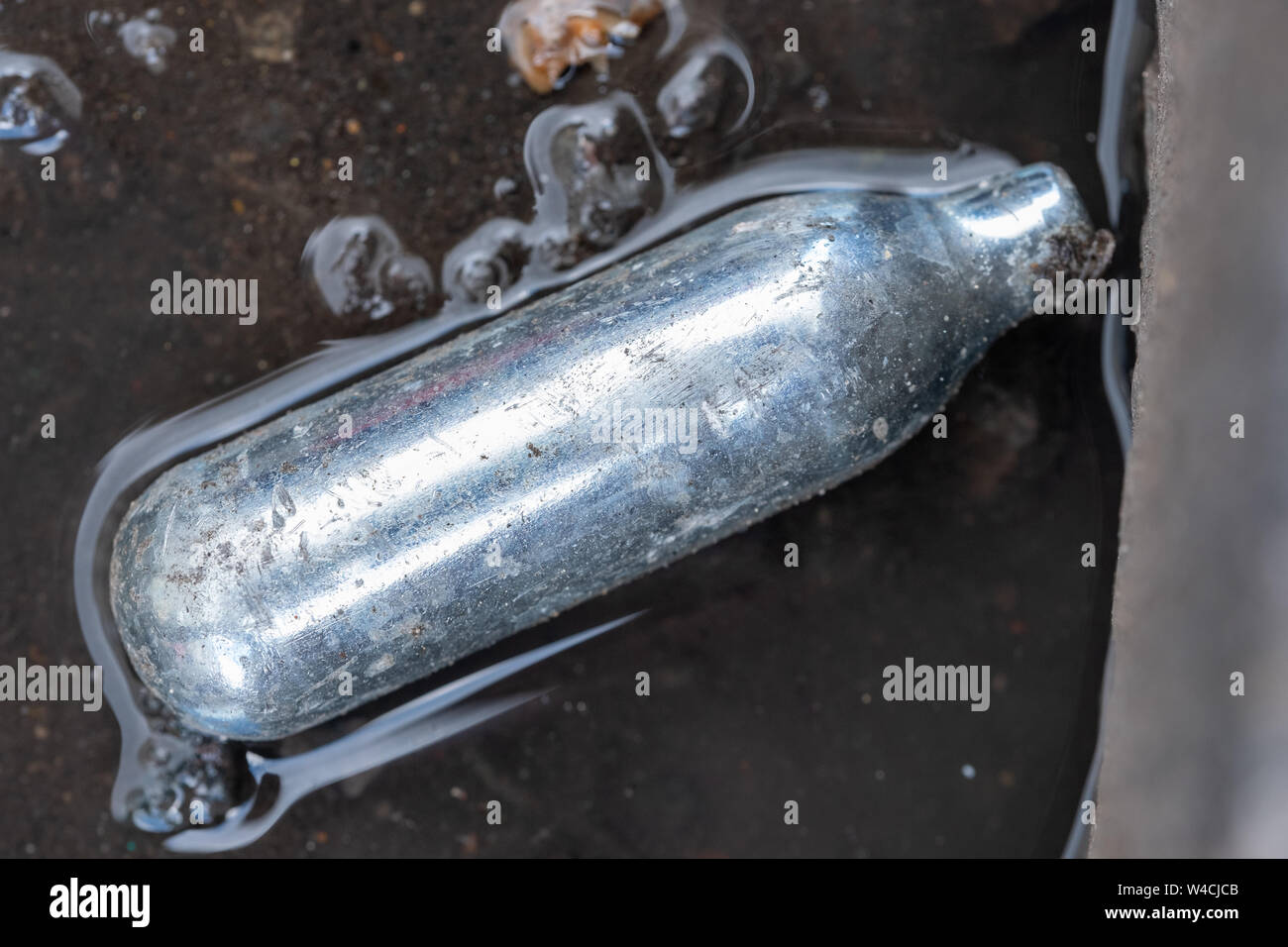 Nitrous oxide canister / cream charger lying in the gutter metal