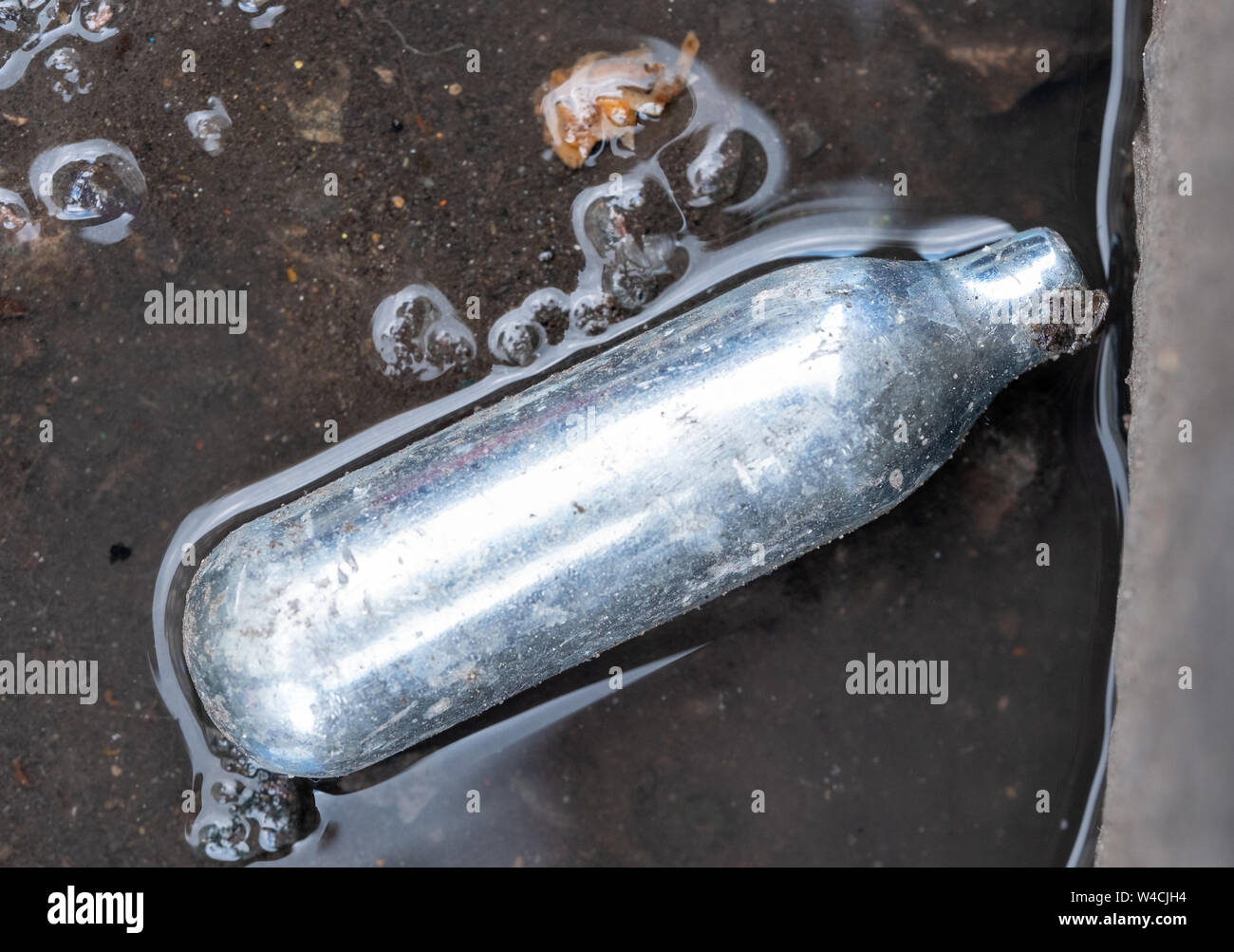 Nitrous oxide canister / cream charger lying in the gutter metal cylinder containing nitrous