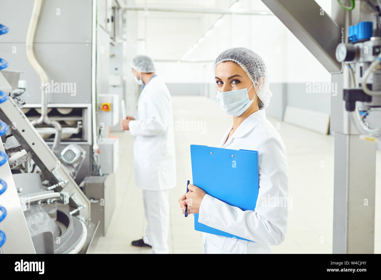 A woman in a white uniform with a folder in her hand controls the production process. Stock Photo