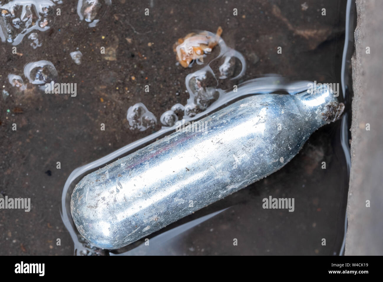 Nitrous oxide canister / cream charger lying in the gutter metal cylinder containing nitrous