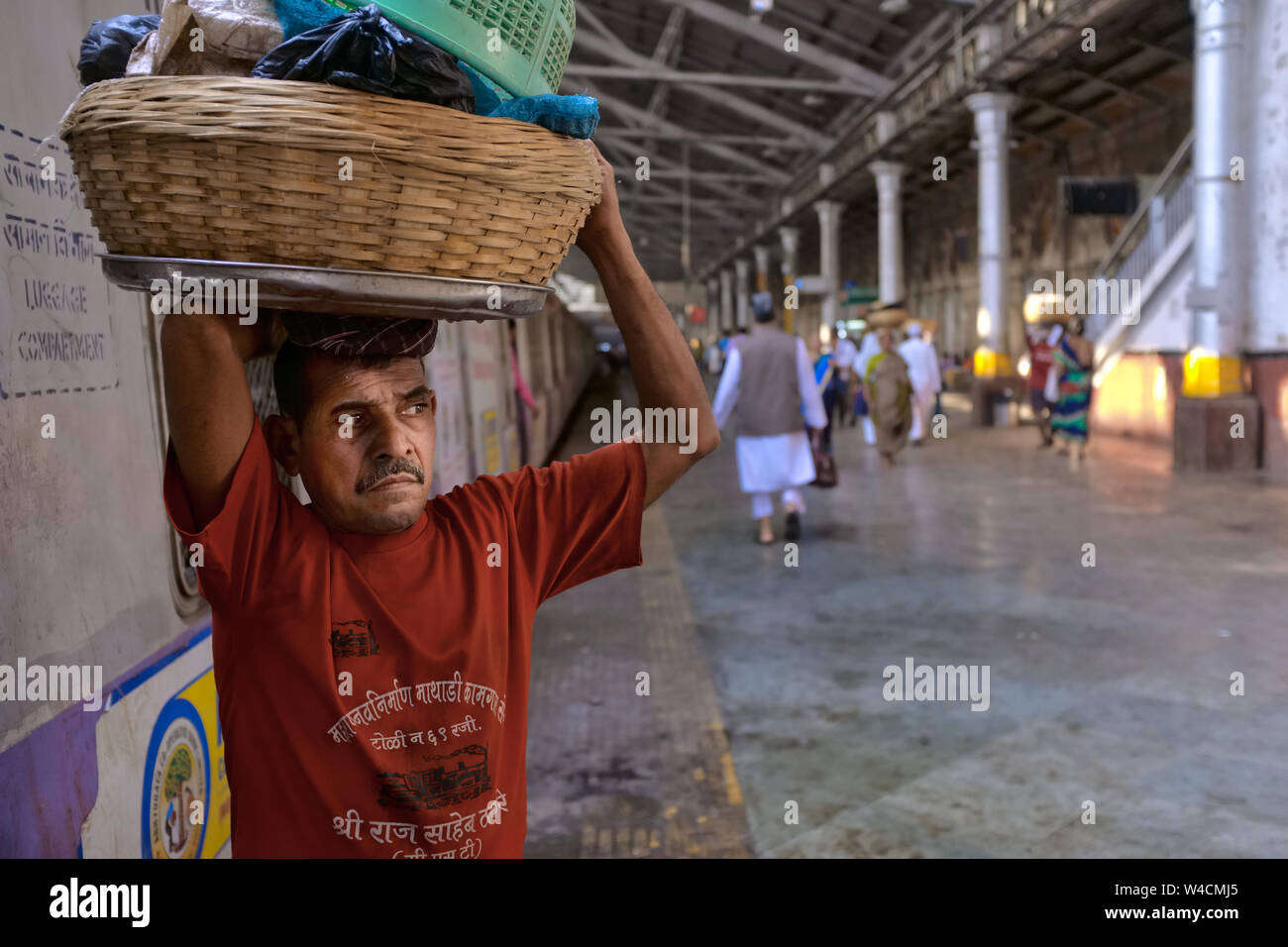 A porter at Chhatrapati Shivaji Maharaj Terminus in Mumbai, India, waiting for a local train to deliver his goods, looking distressed and anguished Stock Photo