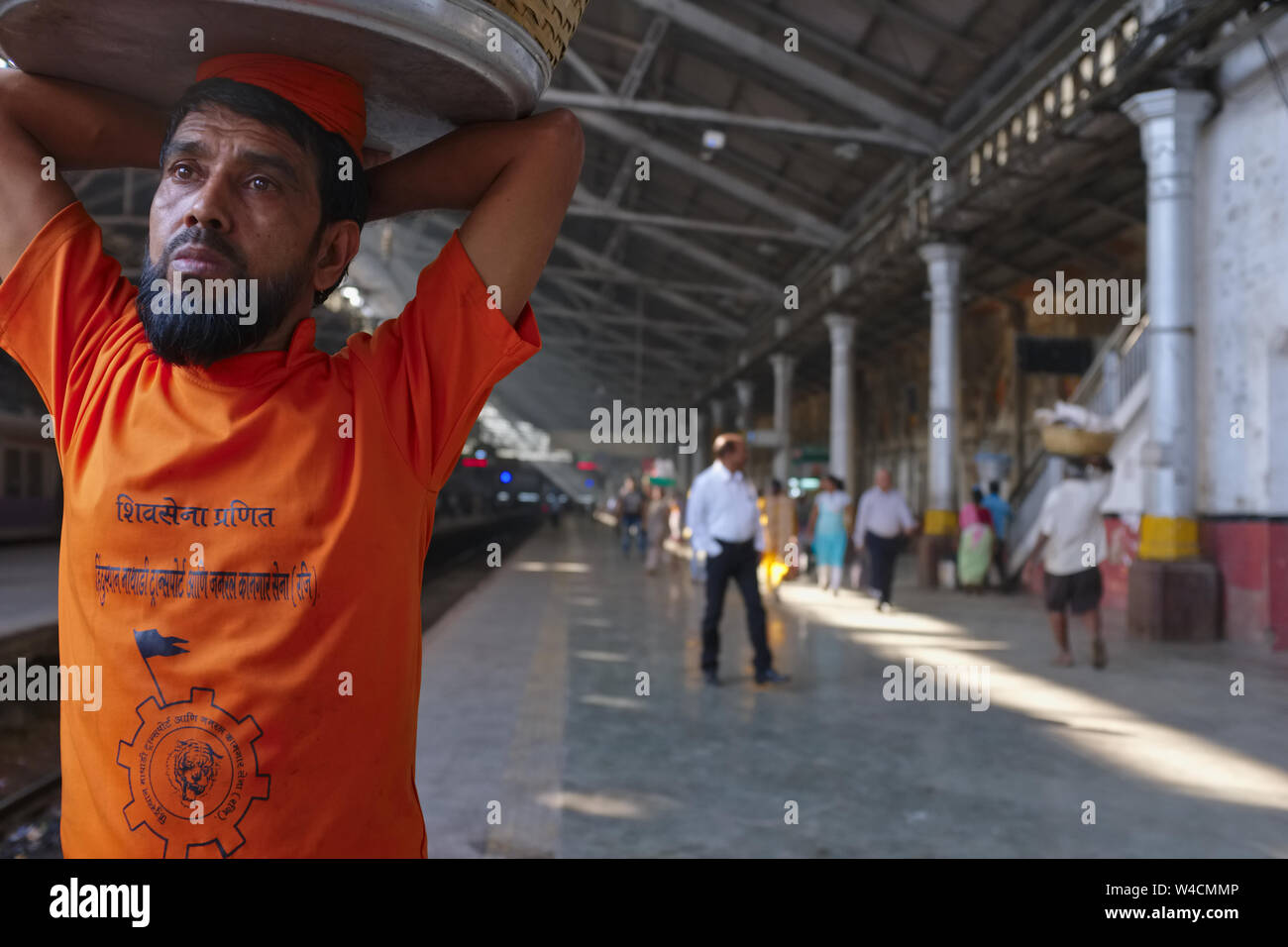A porter at Chhatrapati Shivaji Maharaj Terminus in Mumbai, India, the city's busiest railway station, waiting for a local train to deliver his goods Stock Photo