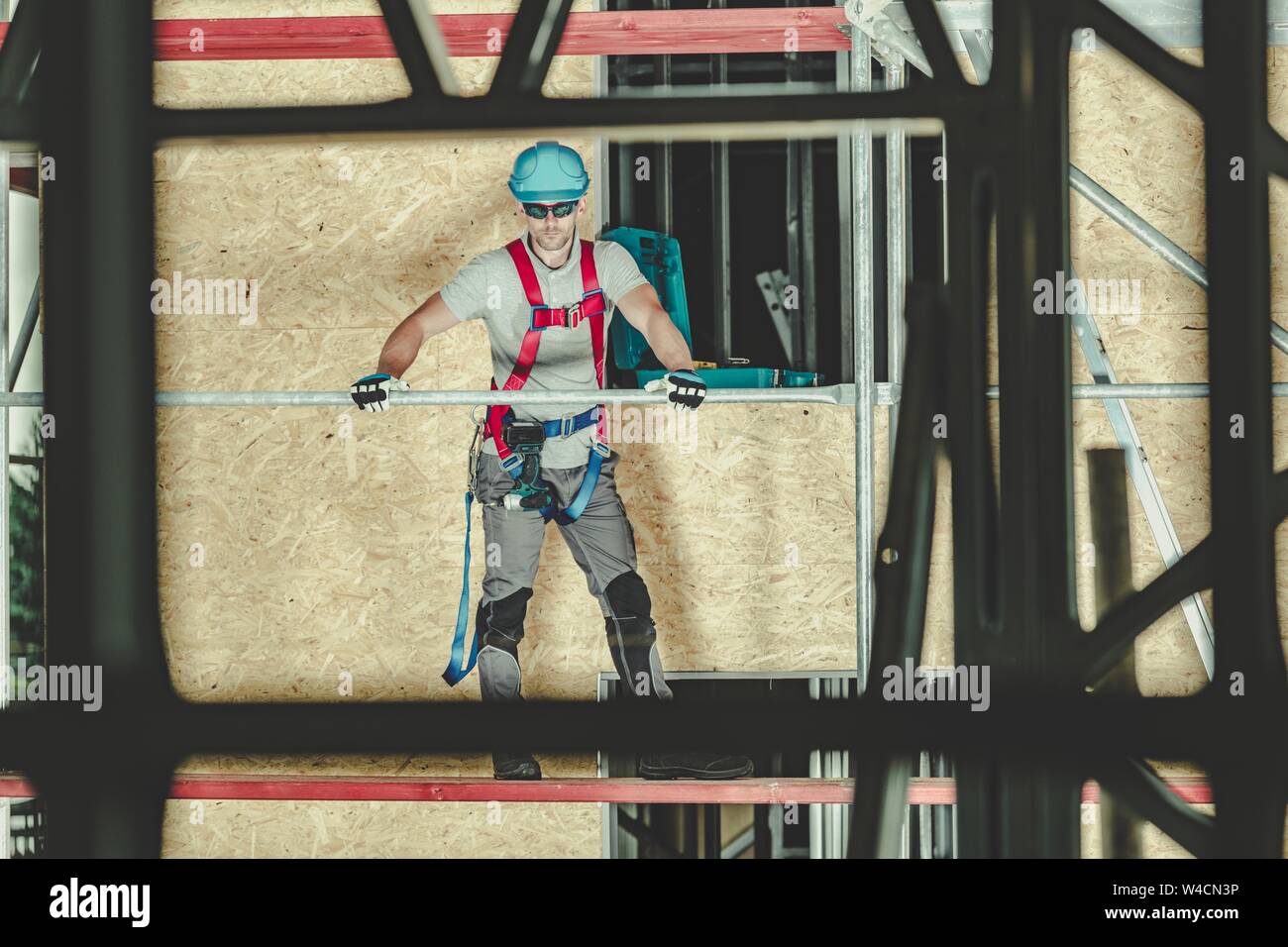 Scaffolding Safety. Caucasian Worker in His 30s Wearing Safety Harness Equipment. Home Building. Stock Photo