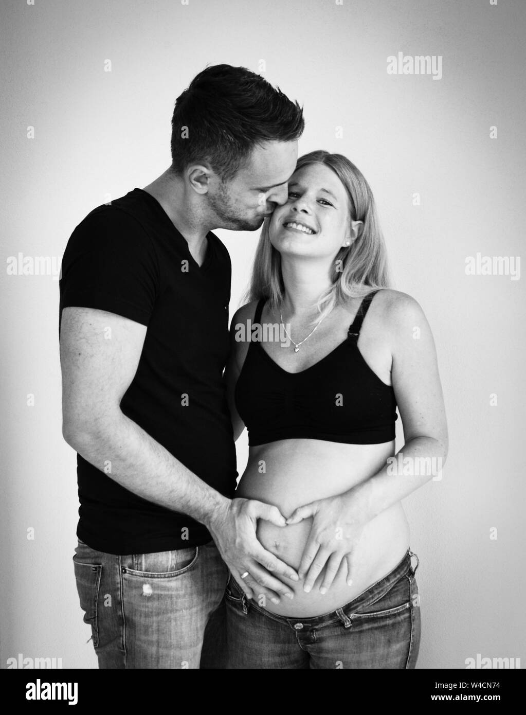pregnant woman with husband hugging and kissing Stock Photo