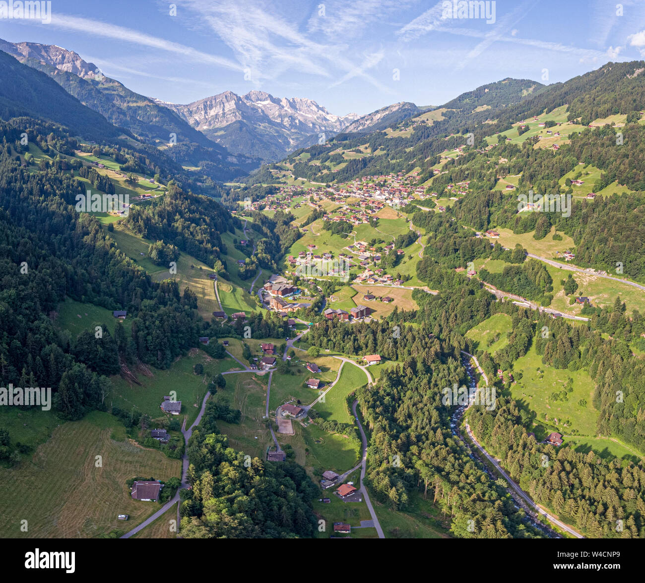 aerial images over an alpine valley and lush green pine forests with ...