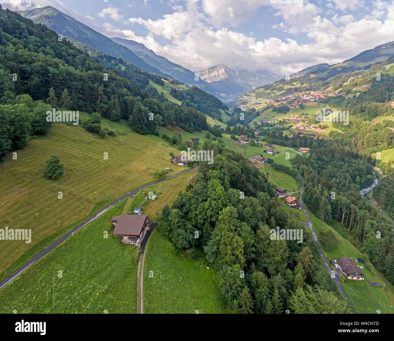 aerial images over an alpine valley and lush green pine forests with ...