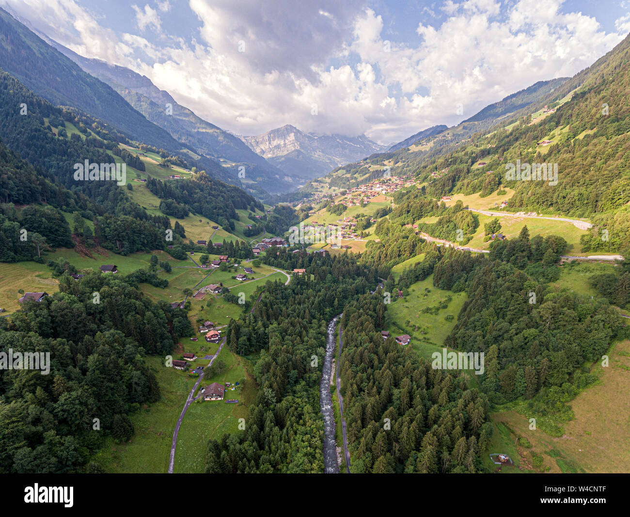 aerial images over an alpine valley and lush green pine forests with ...