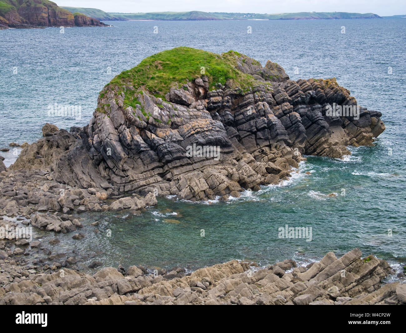 Geological folds and inclines in rock strata in coastal rocks in Pembrokeshire, South Wales, UK, as viewed from the Coast Path. Stock Photo