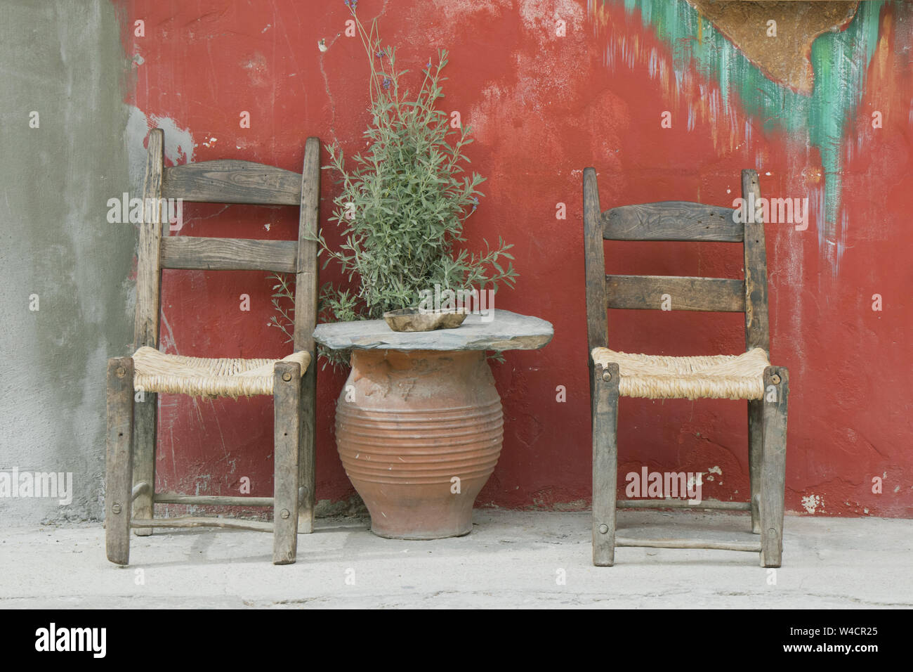 Two chairs on a pavement either side of a Lavender plant in a terracotta pot in Paleochora, South-West Crete, Greece Stock Photo