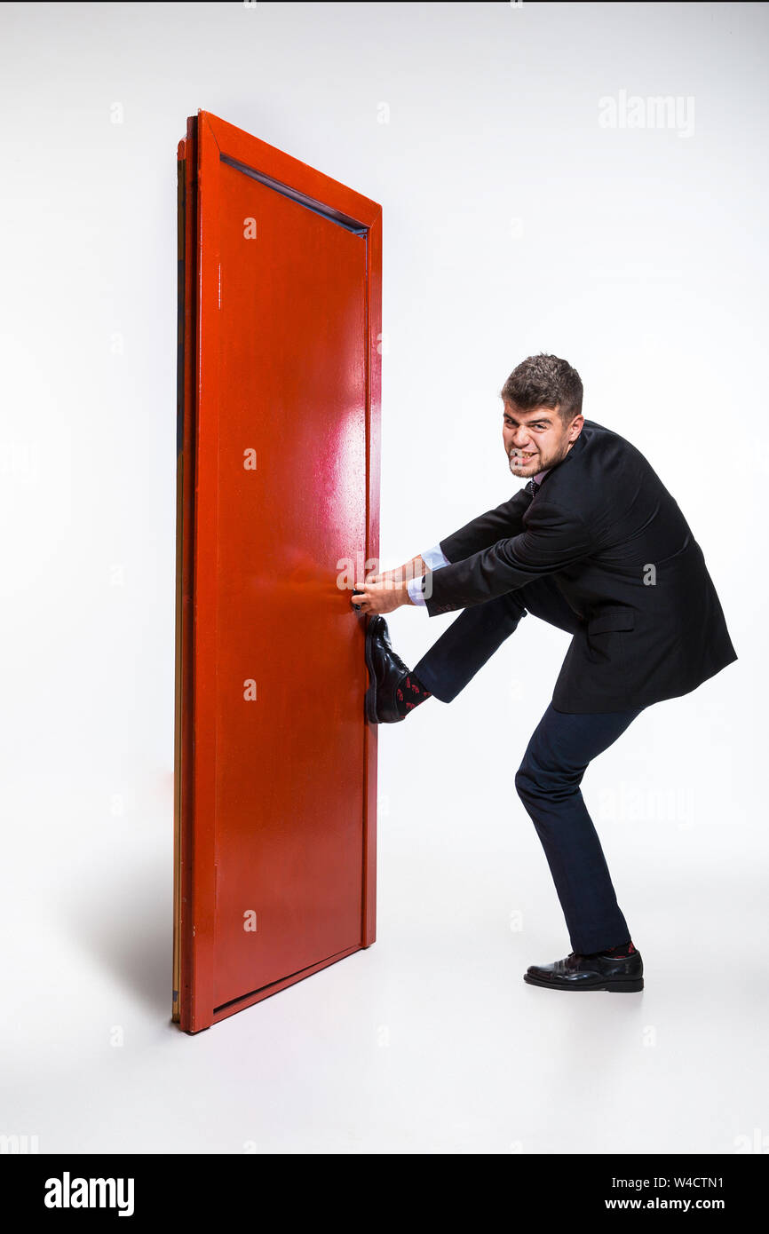 Knocking in emptiness. Young man in black suit trying to open the red door  in career ladder, but it's closed. No way for motivation. Concept of office  worker's troubles, business, problems, stress