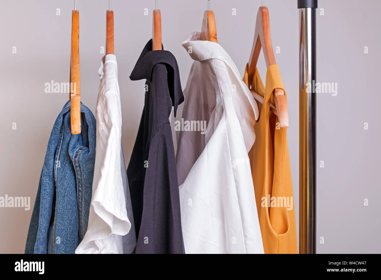 Woman minimalist wardrobe in white and denim on hangers close-up Stock Photo