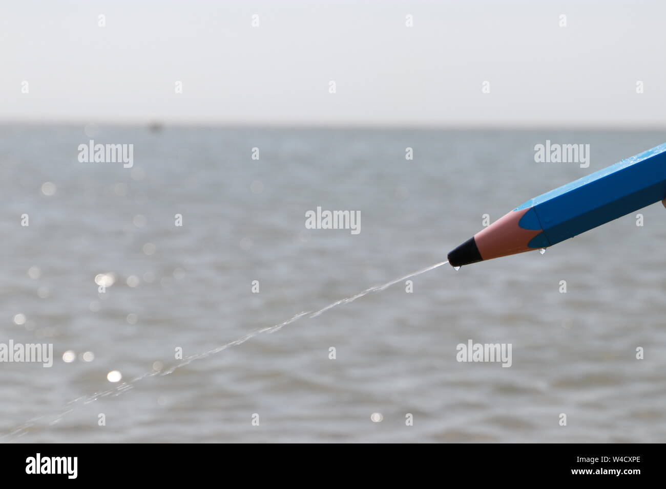 pencil shaped water pistol squirting water, Borkum Stock Photo