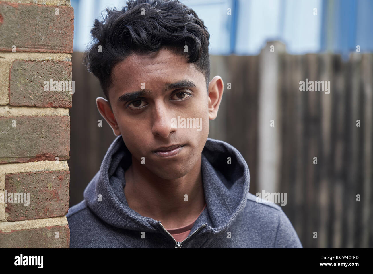 Portrait Of Teenage Boy Leaning Against Wall In Urban Setting Stock Photo