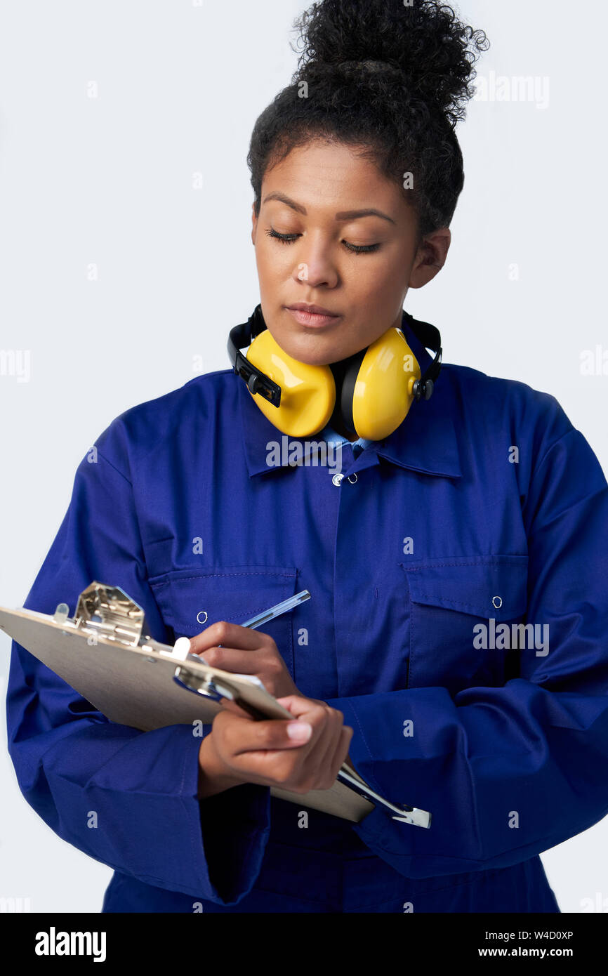 Studio Shot Of Female Engineer With Clipboard And Spanner Against White Background Stock Photo