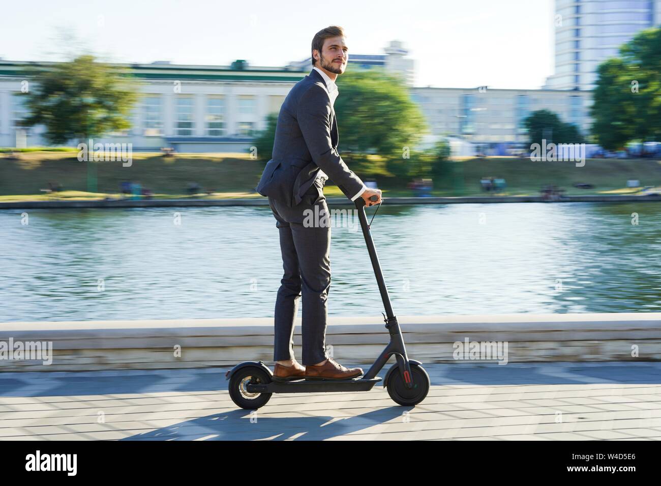Young business man in a suit riding an electric scooter on a business  meeting Stock Photo - Alamy