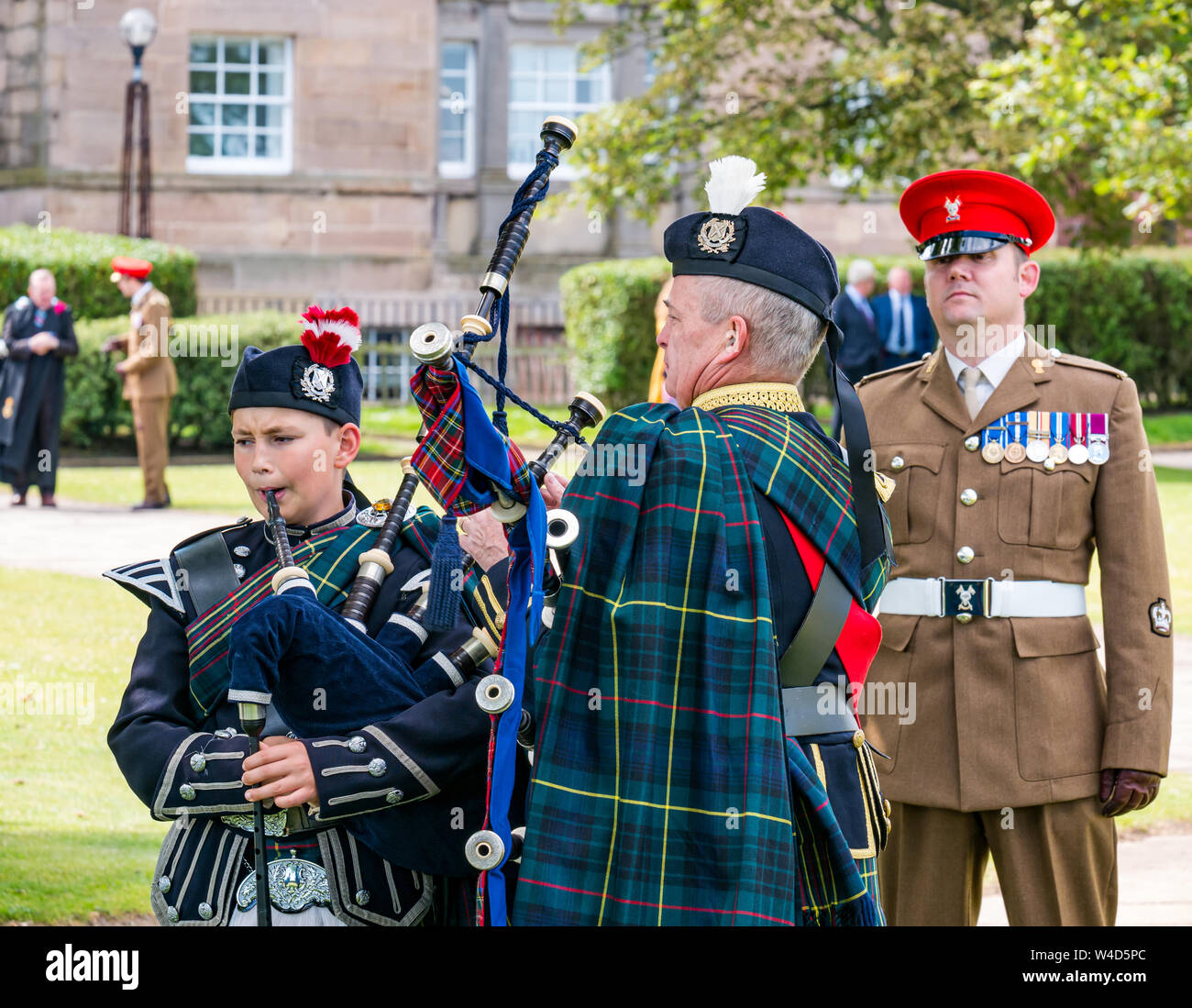 A boy and man in Scottish fromal dress tune bagpipes before ceremony, Dunbar, East Lothian, Scotland, UK Stock Photo