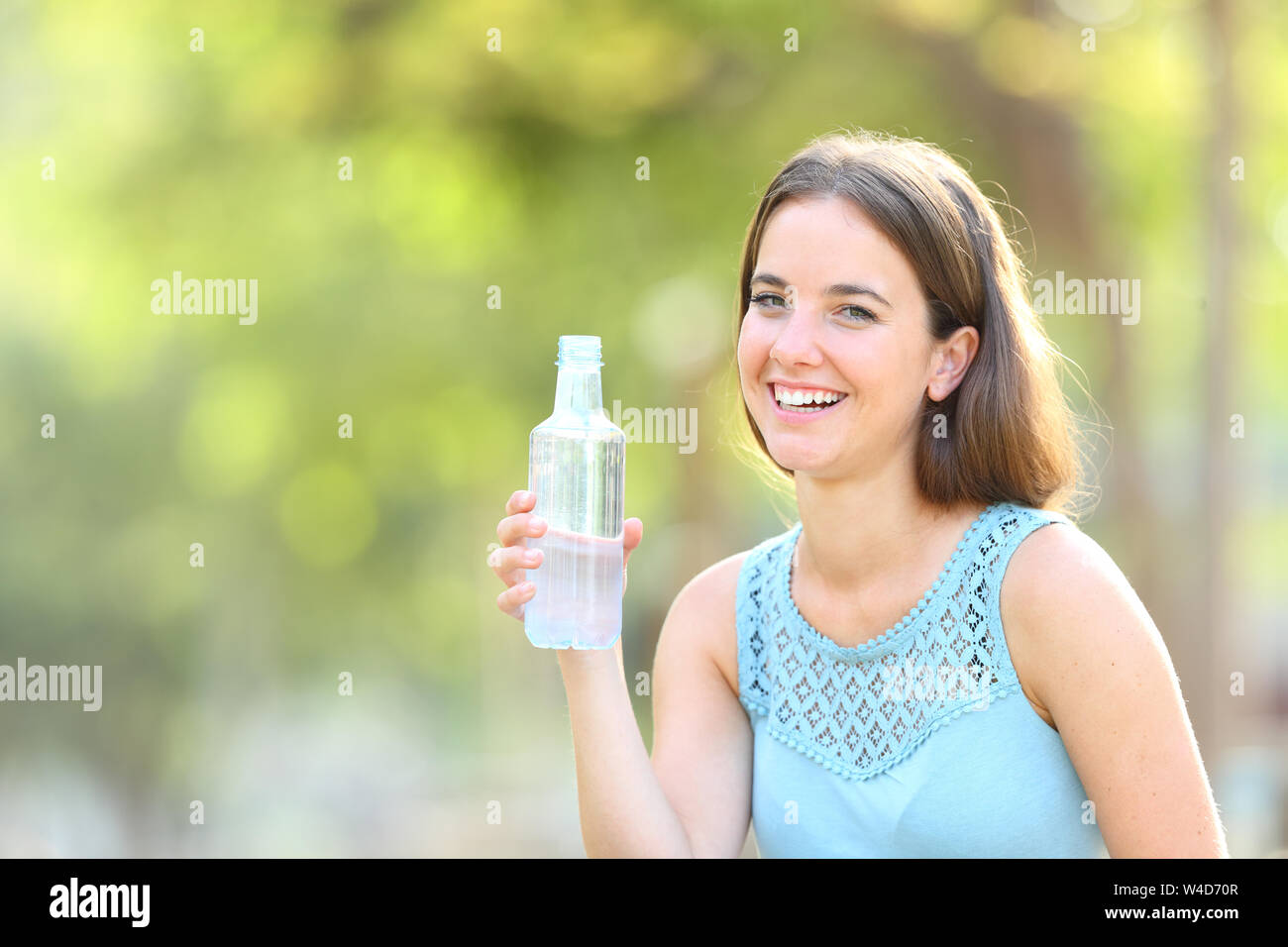 Beautiful teen girl holding bottle of water, smiling and drinking fresh  water Stock Photo