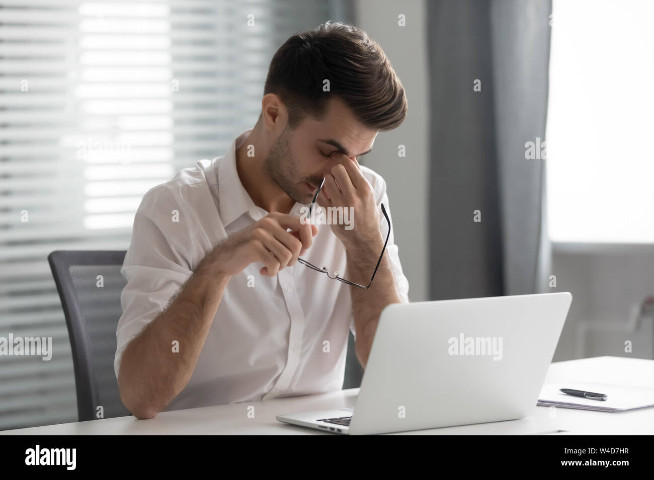 Overworked stressed business man holding glasses massage nose bridge Stock Photo