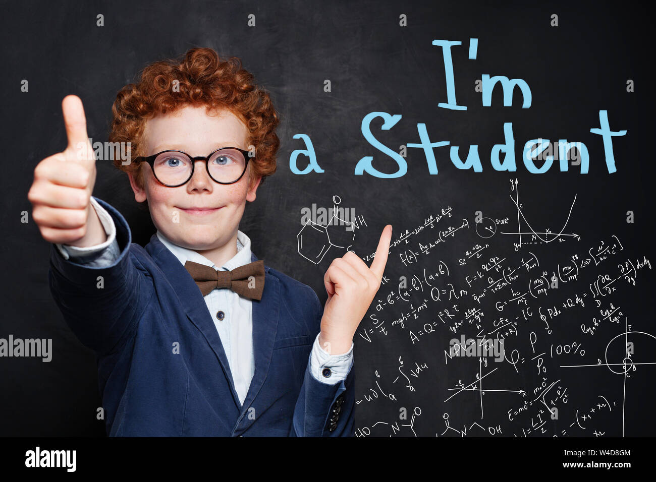Happy curious child boy on blackboard background with science and maths formulas Stock Photo