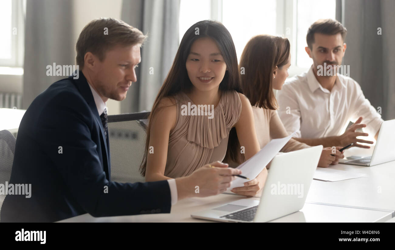 Caucasian male manager mentor teach consult asian female client intern Stock Photo