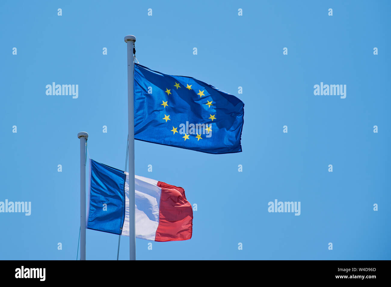 waving European flag and French flag against blue cloudless sky Stock Photo