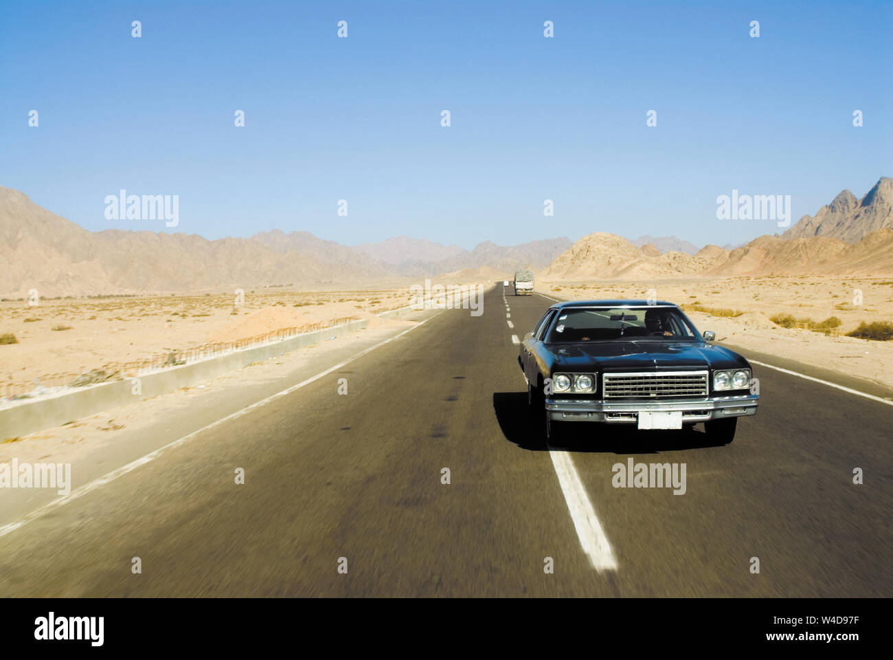 Big black old-fashioned car on a desert highway. Egypt Stock Photo