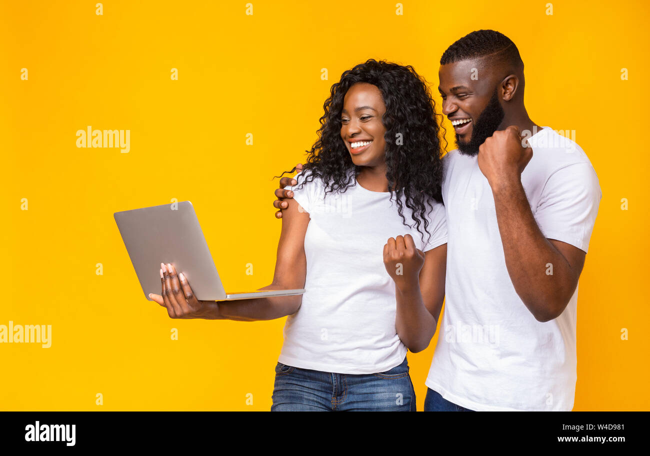 Happy black couple celebrating win with laptop Stock Photo - Alamy