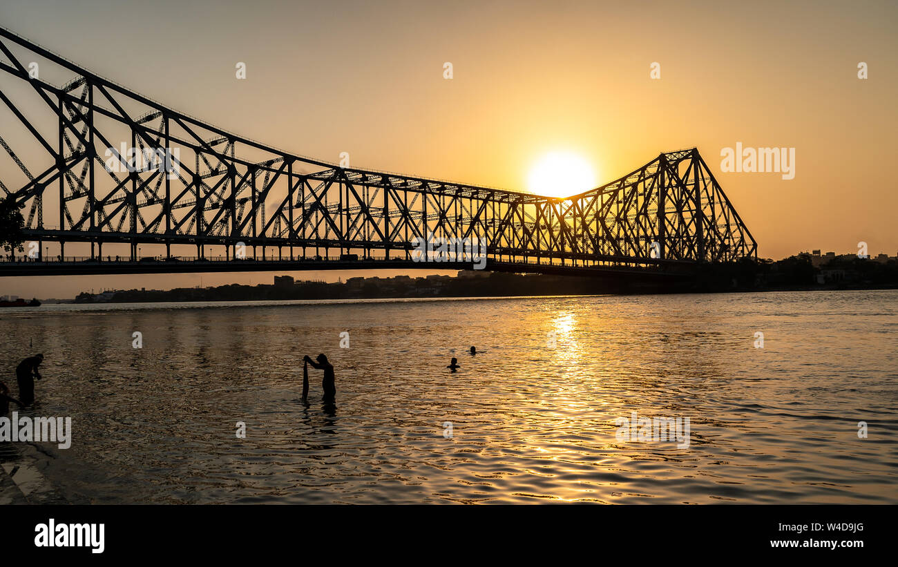 Silhouette of Howrah Bridge at the time of Sunrise.  Howrah Bridge is a bridge with a suspended span over the Hooghly River in West Bengal. Stock Photo