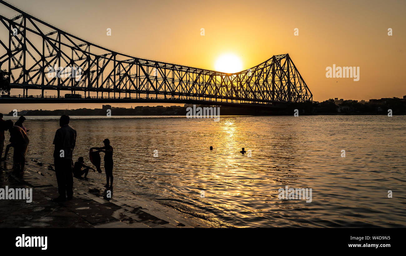 Silhouette of Howrah Bridge at the time of Sunrise.  Howrah Bridge is a bridge with a suspended span over the Hooghly River in West Bengal. Stock Photo