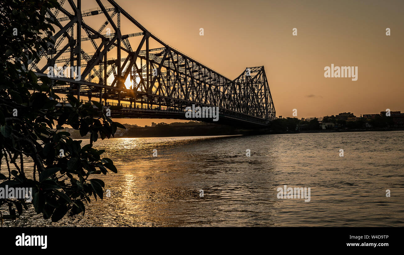 Silhouette of Howrah Bridge at the time of Sunrise.  Howrah Bridge is a bridge with a suspended span over the Hooghly River in West Bengal. Stock Photo