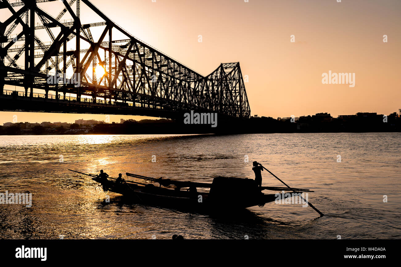 Silhouette of Howrah Bridge at the time of Sunrise.  Howrah Bridge is a bridge with a suspended span over the Hooghly River in West Bengal. Stock Photo